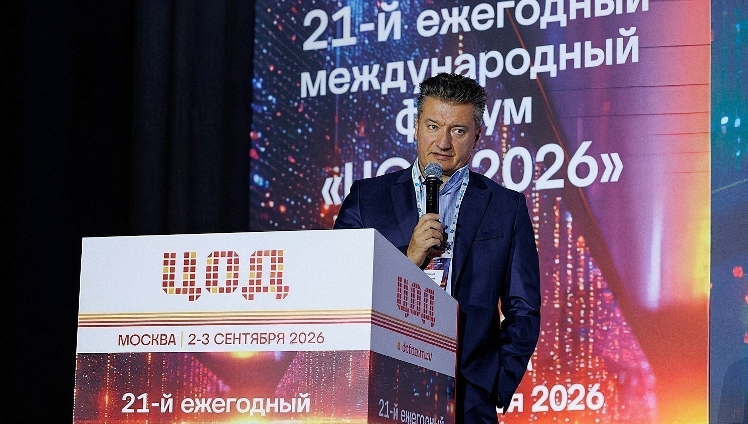 Выступающий у трибуны с логотипом форума рассказывает залу о развитии дата-центров
