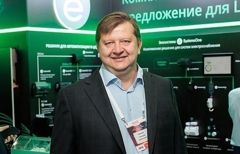 Участник форума у стенда с зелёной подсветкой и схемой комплексного решения для электроснабжения