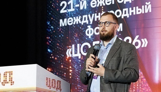 Выступающий в очках и сером пиджаке за трибуной с логотипом «ЦОД»