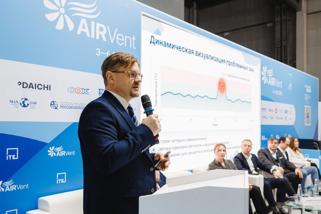 Докладчик с микрофоном выступает перед залом на деловой программе AIRVent, на экране позади него слайд презентации