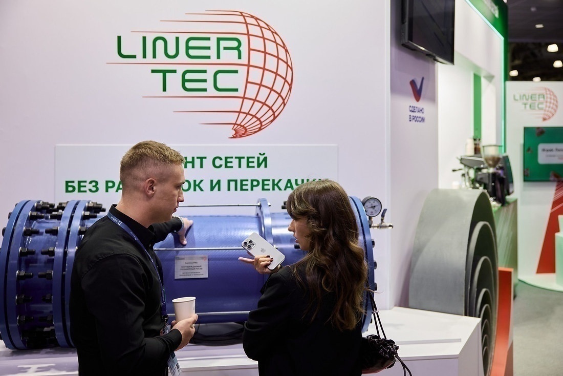 Посетители у стенда Liner Tec с фрагментом синего трубопровода, на стене слоган о ремонте сетей без раскопок